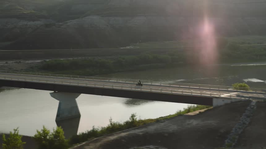 Aerial shot of a motorcycle riding over a bridge