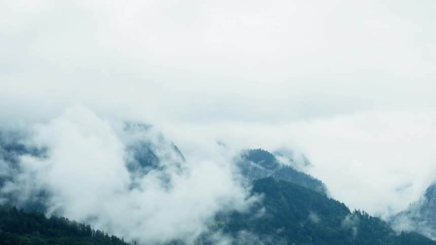 A misty mountain range rises through low clouds and fog