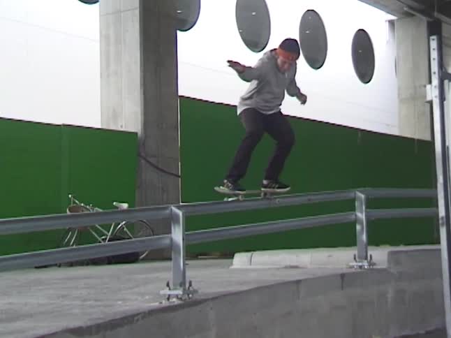 Skateboarder performing a trick on a metal handrail in an urban setting