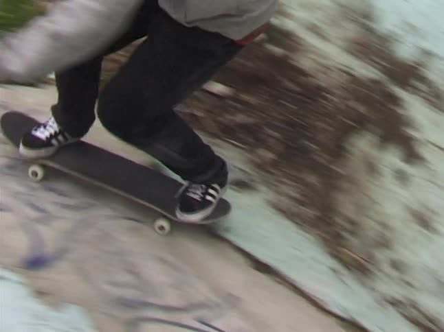 The teenager falls off his skateboard at the bottom of the ramp