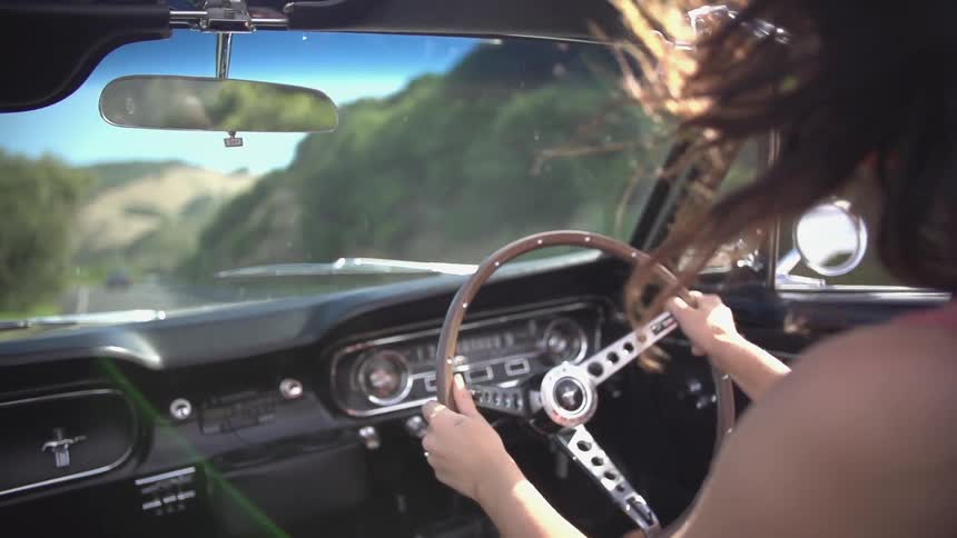 A woman driving a car on a road on a sunny day
