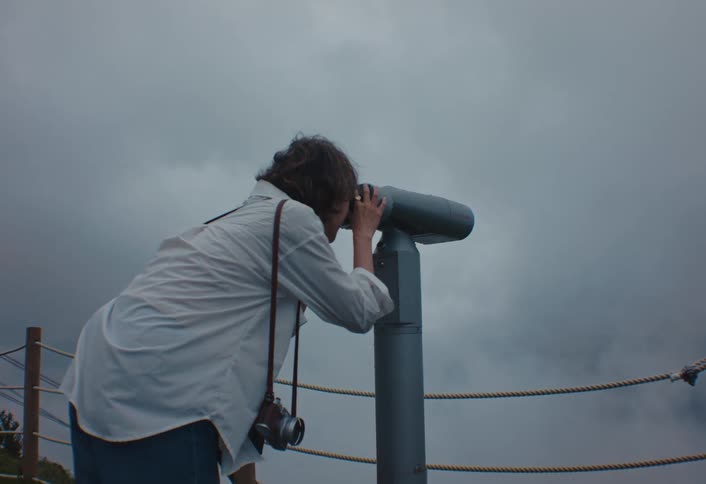 The woman is looking through binoculars through the fog