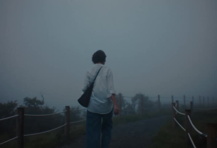 A young woman walking through a narrow road in a rural area on a cloudy day