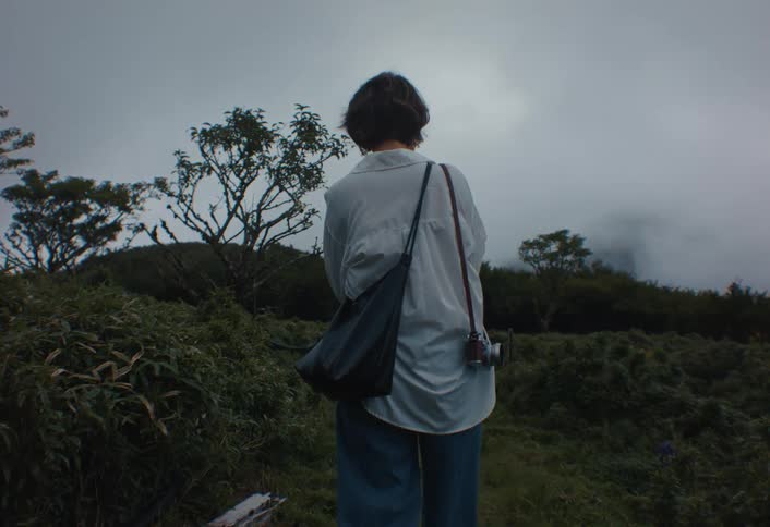 A young woman walking through an outdoor field on a cloudy day