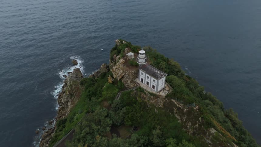 White lighthouse located atop a rocky promontory surrounded by the sea