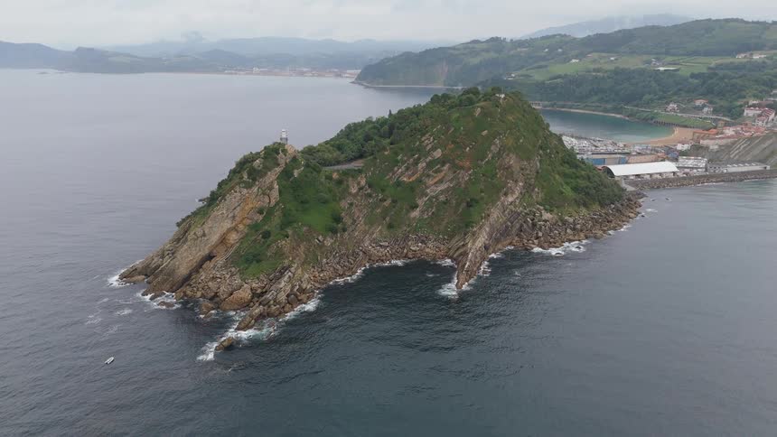 Rocky formation covered with vegetation extending into the sea with a lighthouse on top