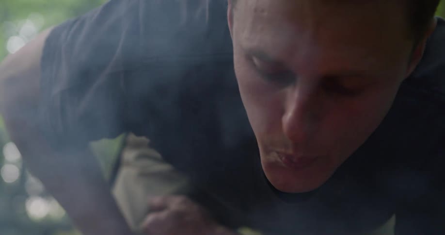 Man blowing to fuel a fire in an outdoor setting