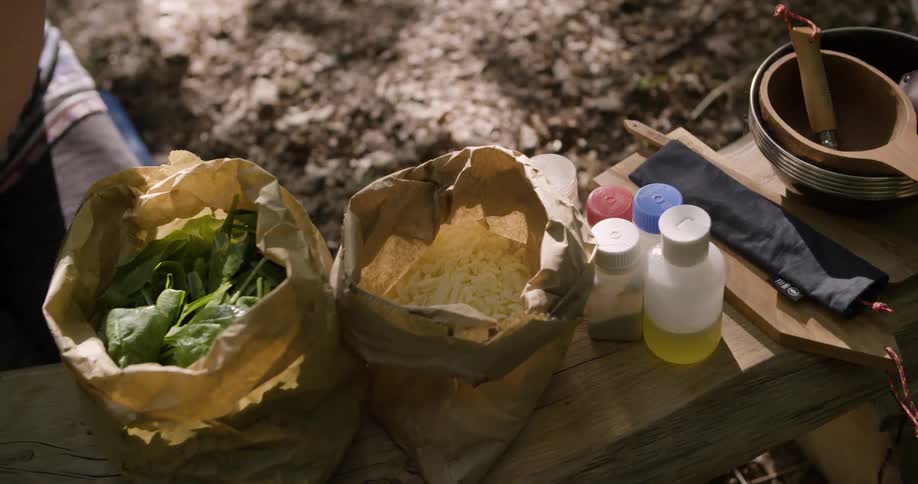 The woman has ingredients and cooking tools at the camp site