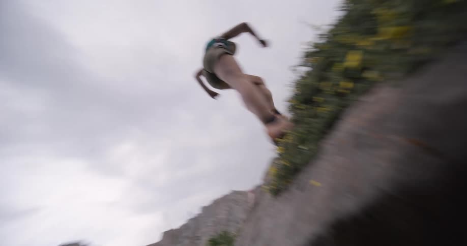 Woman in motion leaps over sloped terrain with a mountain in the background