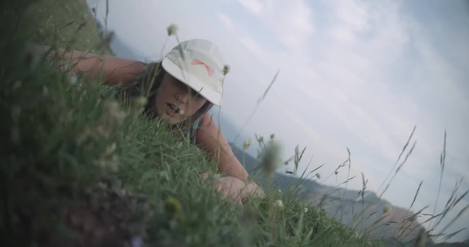 A young woman falling with her face on a field outdoors during daytime