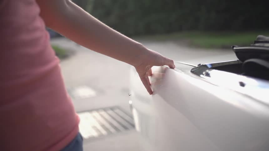 Woman touching the side of a car