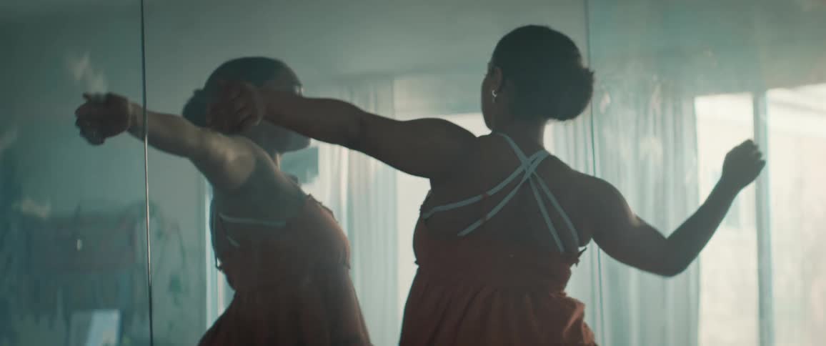 The woman dances in front of the mirrored wall