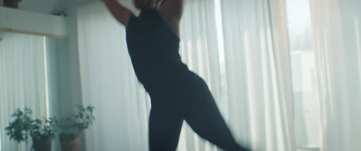 Woman in black clothing dancing in a naturally lit space