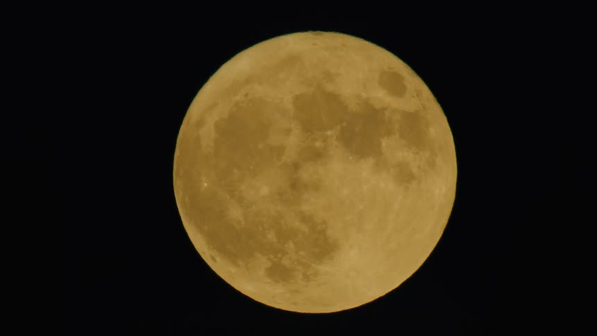 Golden full moon standing out against the night sky