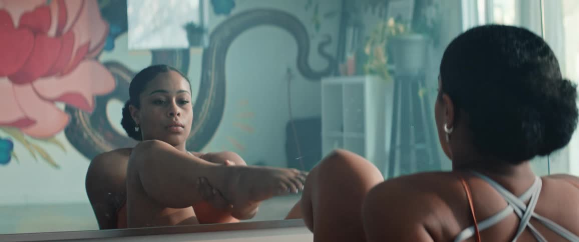 The woman raises her leg in front of the mirror