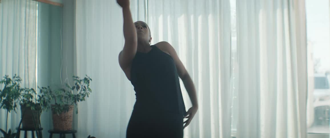 A young black woman practising and dancing in a room during daytime