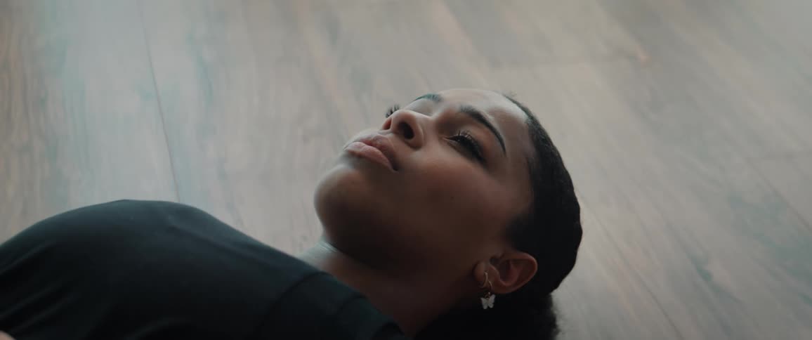 Woman lying on the floor with a relaxed expression in an indoor setting