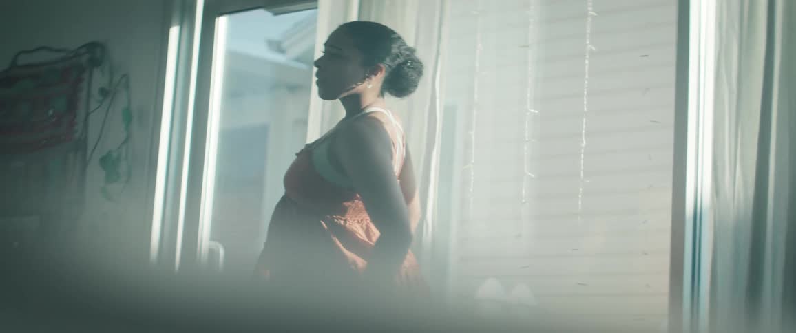 A young woman dances alone indoors at midday moving gracefully as sunlight streams through the windows