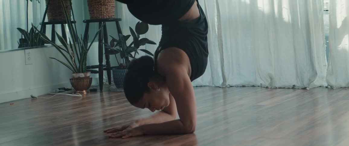 The woman does a handstand as she dances