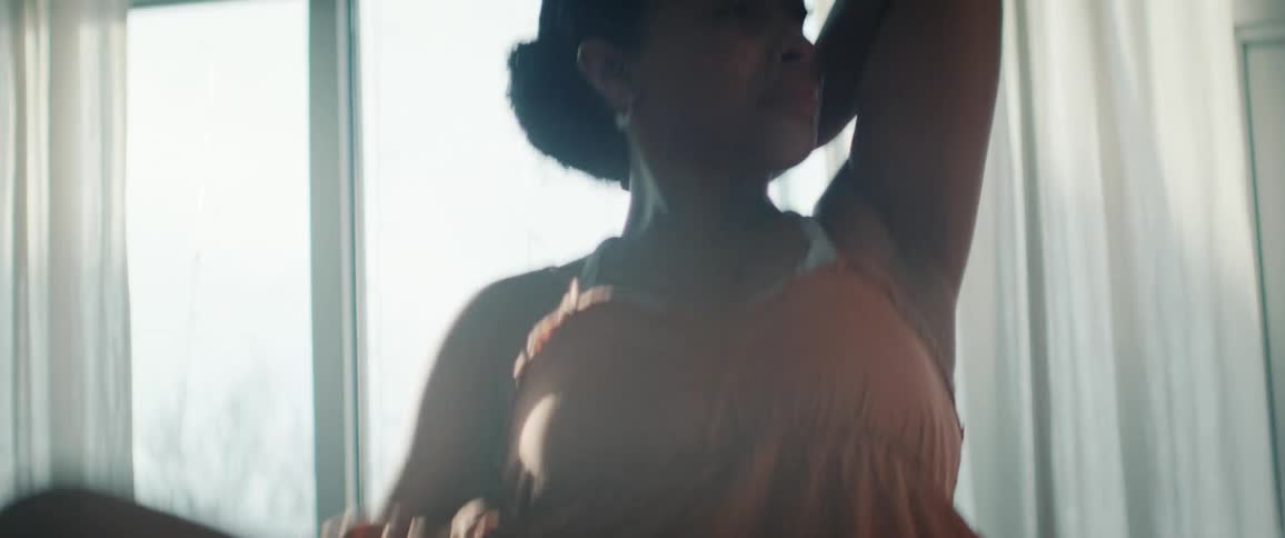 A young black woman practices ballet indoors at midday