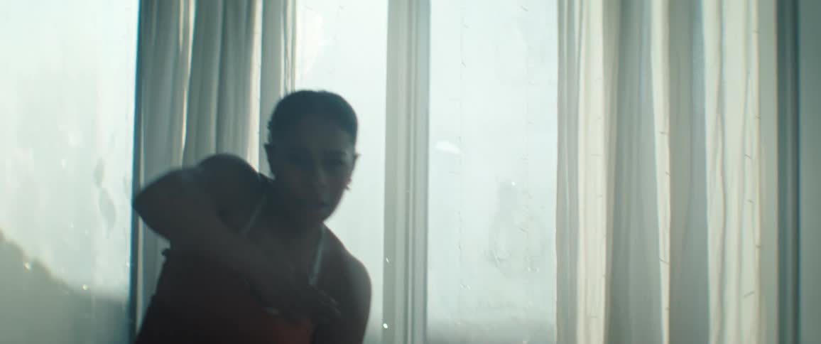 Woman in an orange dress dancing in front of a window lit by natural light