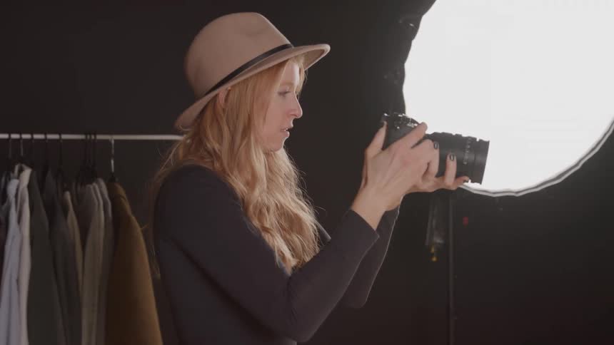 Woman wearing a hat adjusts the framing in a welllit studio