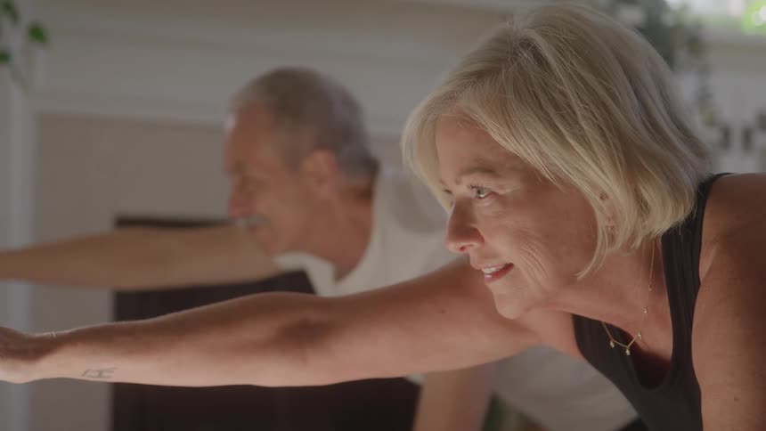 Smiling woman extends her arm forward during exercise alongside a man