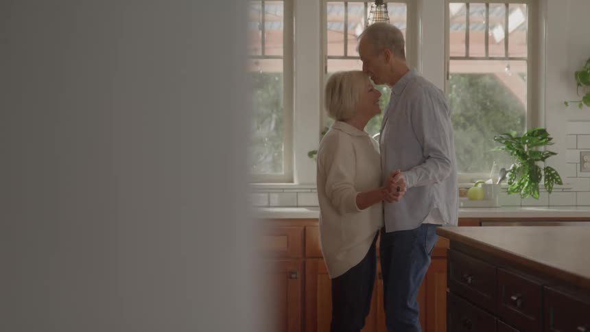 Mature couple dances together in the kitchen in an affectionate moment
