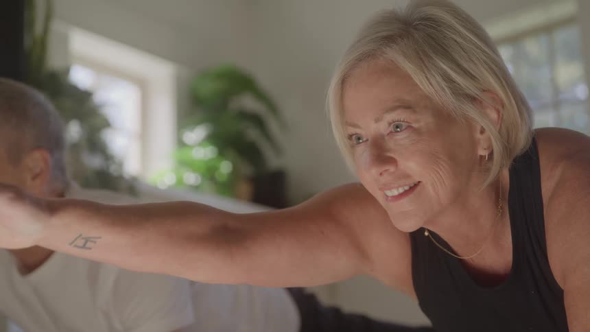 Woman smiles while maintaining balance with her arm extended next to a man