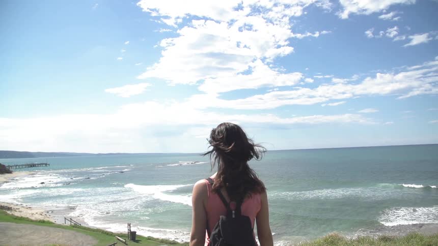 Woman walks towards the ocean