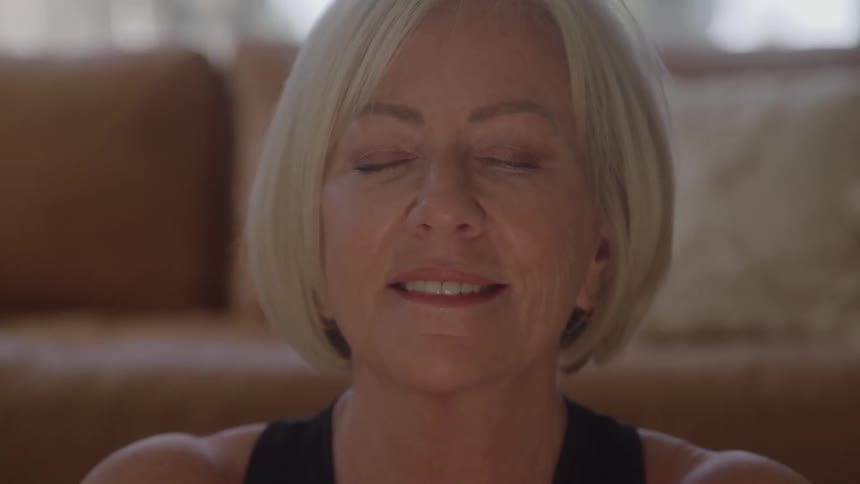 White adult woman indoors in a living room smiling with her eyes closed during day time