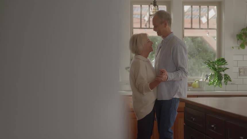 Mature couple shares a moment of affectionate dancing in the kitchen