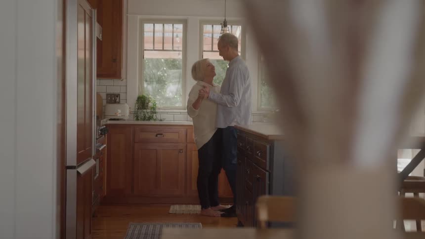 Mature couple dances together in the kitchen in a tender mood
