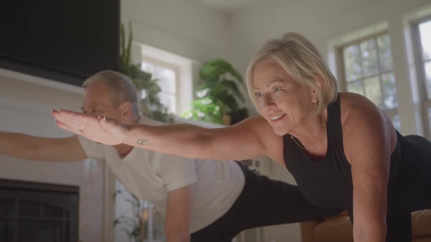 Couple performs a balancing pose with arms extended during yoga practice