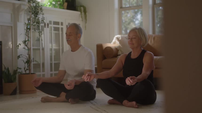 Couple seated in lotus position meditates in a bright setting