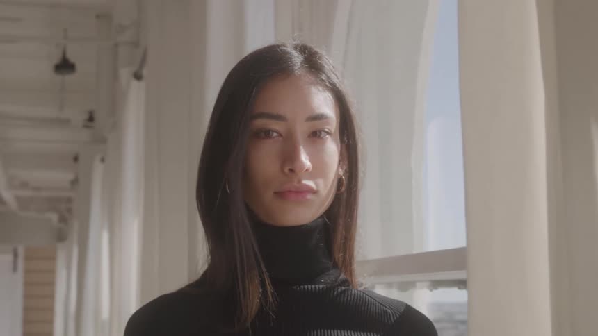 Close up of a young woman standing by the window in a corridor during daytime