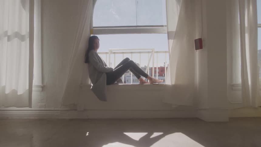 A woman sits on a windowsill