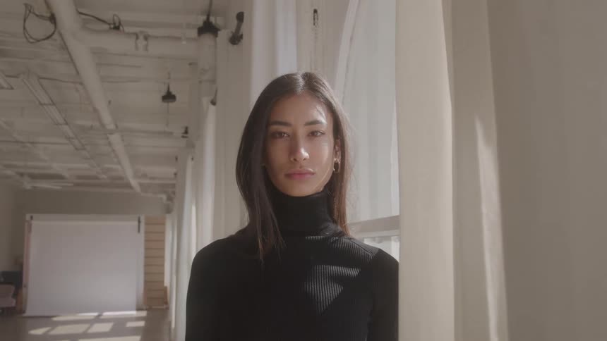 Close up portrait of a young woman standing by the window in a corridor during daytime