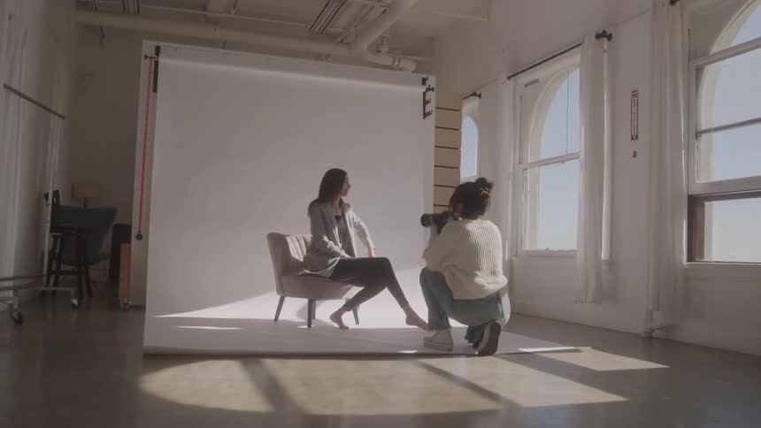 The model is sitting while having her photo taken