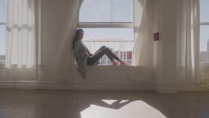 Woman sits on the windowsill enjoying the natural light of the studio