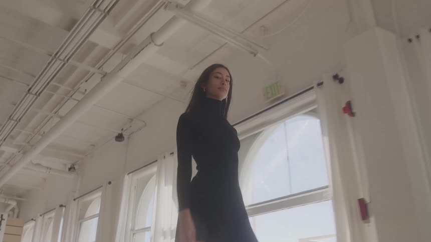 The model is walking through the studio in a black dress