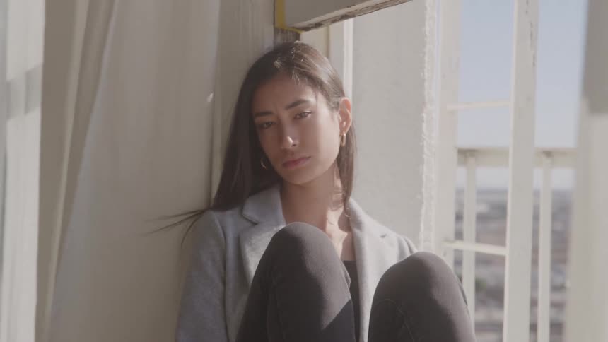 The woman is sitting on the windowsill