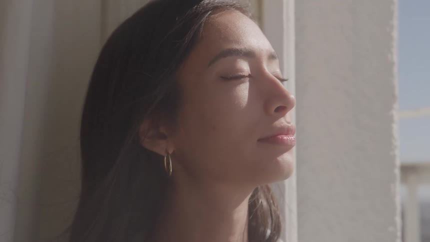Wind blows the womans hair by the window