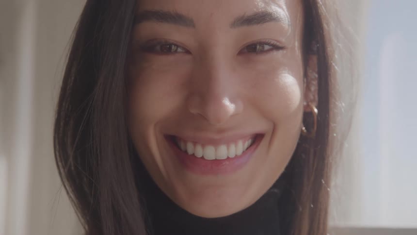 A radiant woman with long dark hair smiling contentedly in warm natural light