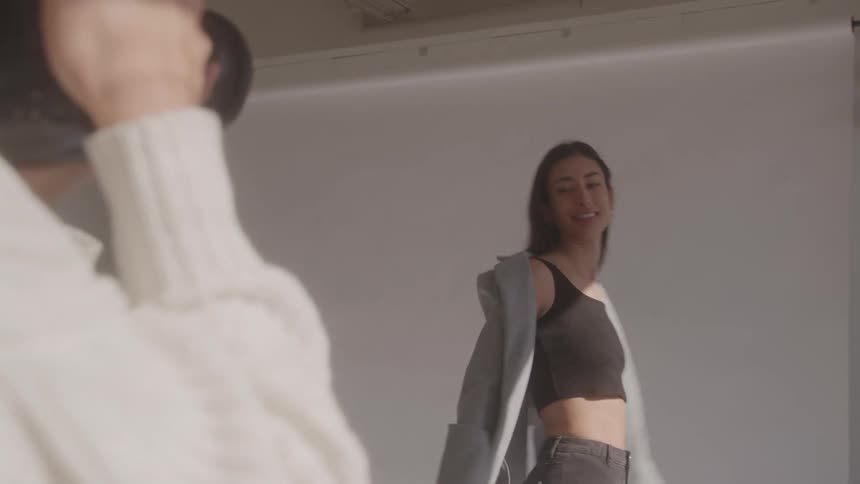 Young female model posing and smiling while a female photographer takes a picture indoors during day time