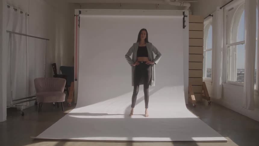 The model is posing in a blazer in front of the backdrop