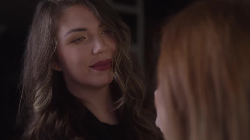 Female makeup artist applying makeup to a womans face indoors
