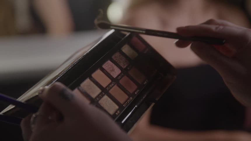 Close up of a makeup artist holding a makeup palette during a makeup session in a studio
