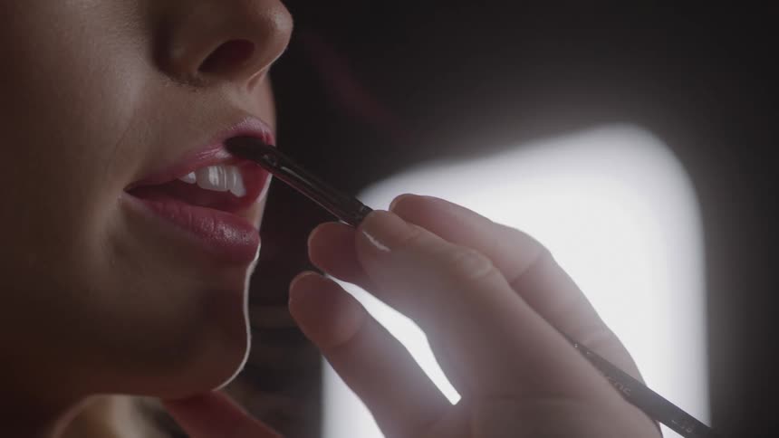 Lipstick is being put on the woman