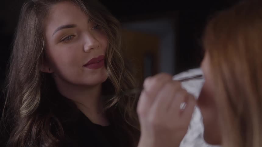 The makeup artist smiles while working on a model